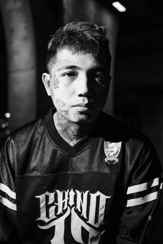 a black and white photo of a man with tattoos, a black and white photo, inspired by Xi Gang, wearing a tracksuit, brian pulido, heavy eyes to the side, gnoll