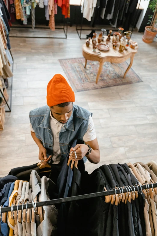 a man standing in front of a rack of clothes, looking down from above, sitting on a store shelf, sustainable materials, gen z