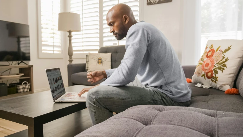 a man sitting on a couch using a laptop, ray lewis, profile image, home office, multiple stories