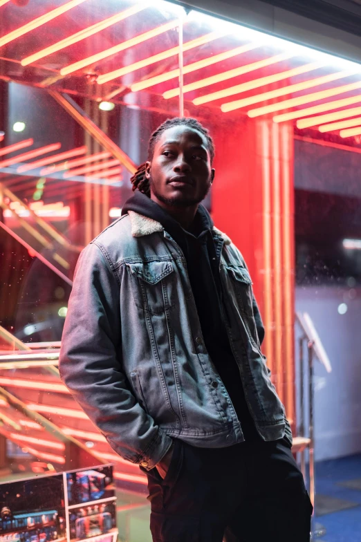 a man standing in front of a neon sign, an album cover, trending on pexels, realism, kendrick lamar, all black cyberpunk clothes, looking to camera, actor