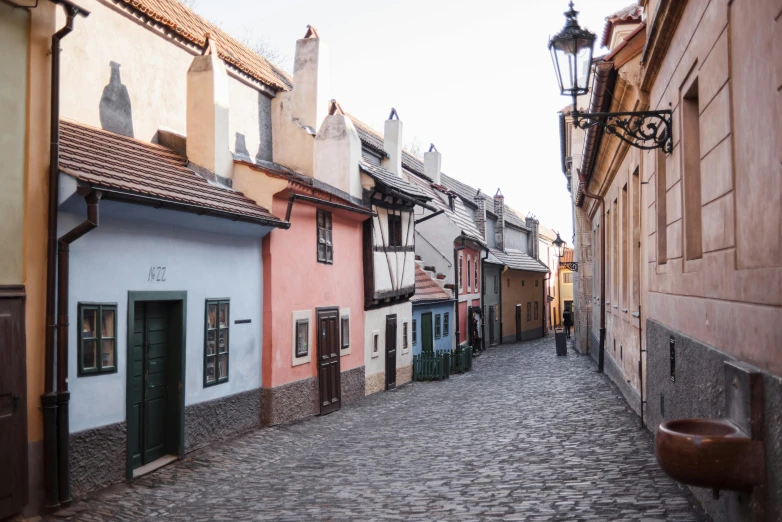 a cobblestone street in a european city, by Emma Andijewska, pexels contest winner, art nouveau, muted pastel colors, cottages, prague, low ultrawide shot