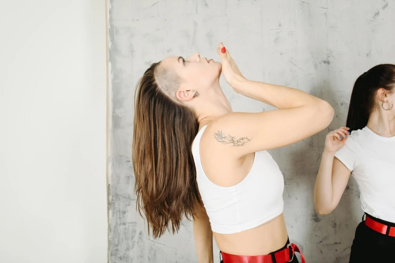 a couple of women standing next to each other, a tattoo, trending on pexels, antipodeans, brunette fairy woman stretching, shaved face, profile image, wearing a cropped top