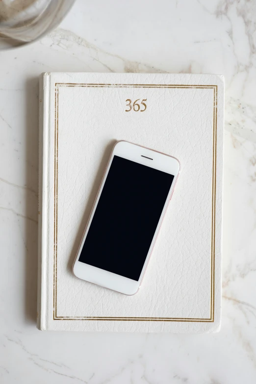 a white cell phone sitting on top of a book, a picture, 8 1 5, flat lay, luxury journal cover, iphone 13