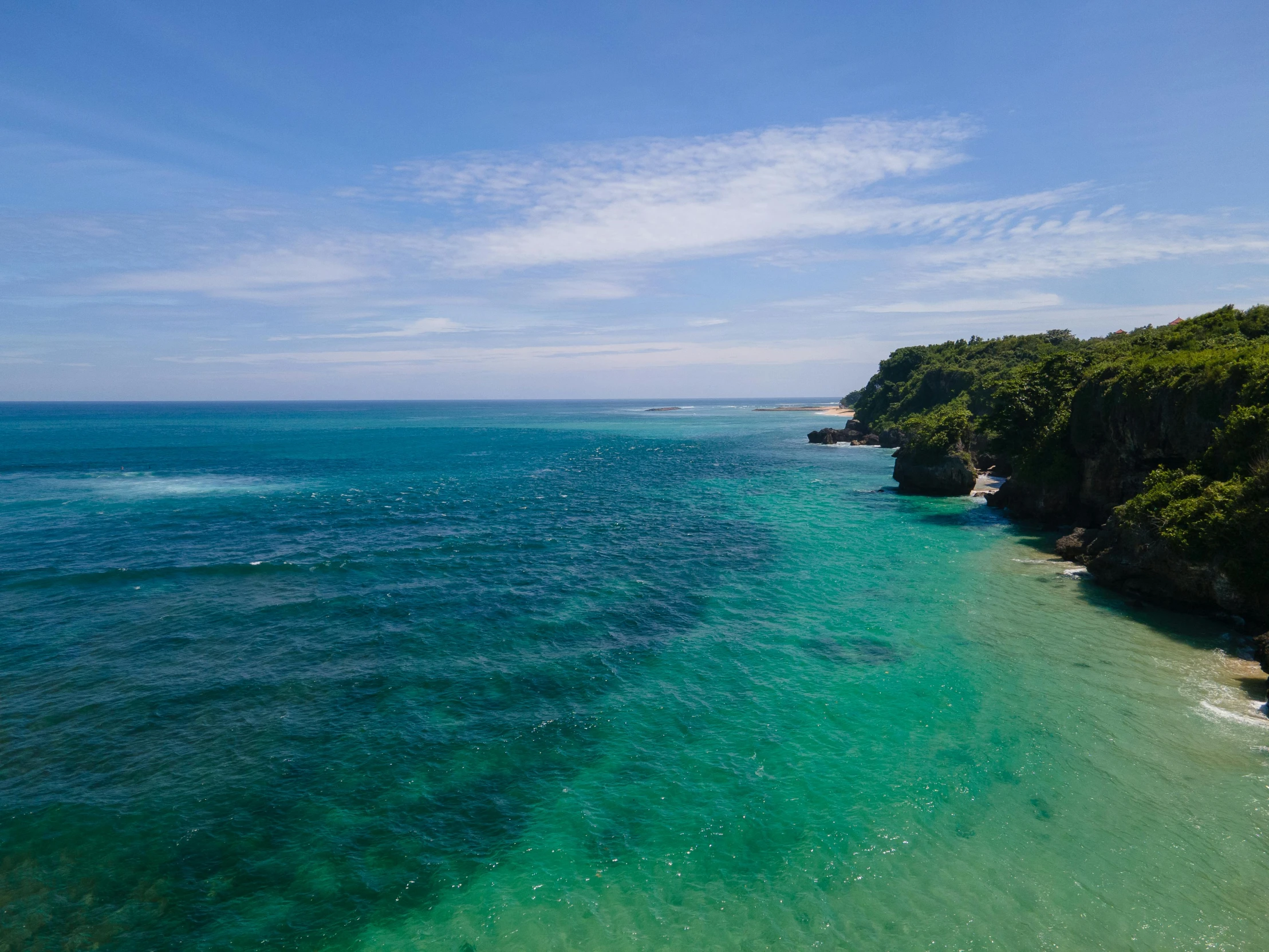 a large body of water next to a lush green hillside, pexels contest winner, sumatraism, australian beach, light blue water, fishing, looking down a cliff