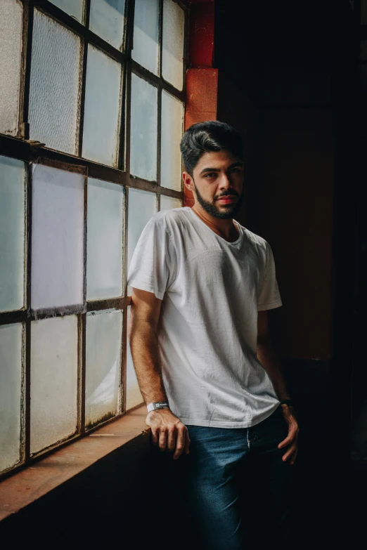 a man standing in front of a window, by Adam Dario Keel, dressed in a white t shirt, mahmud barzanji, promo image, concert photo