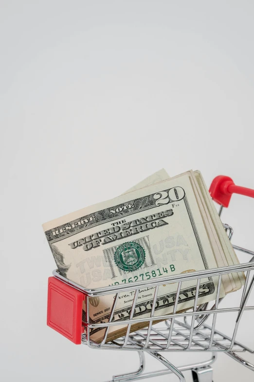 a shopping cart filled with money sitting on top of a table, product image