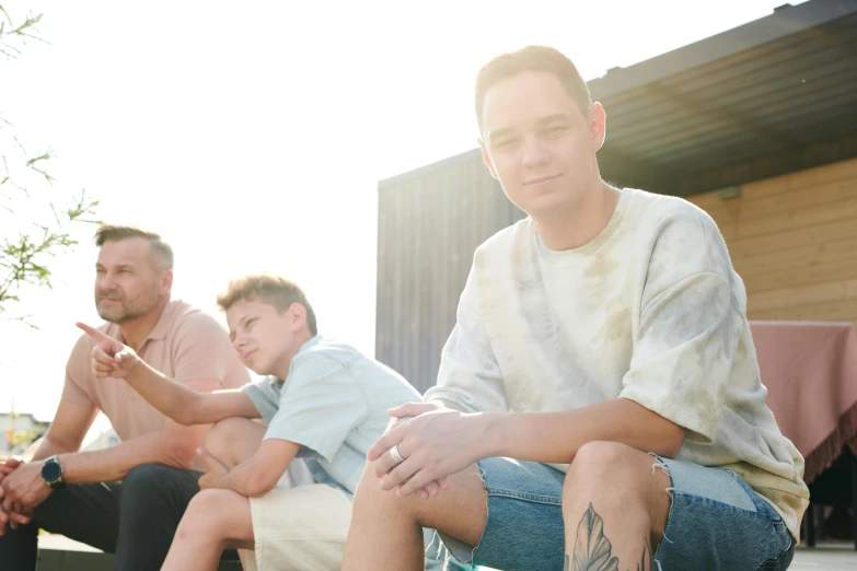 a group of young men sitting next to each other, a portrait, pexels, happening, golden hour photo, husband wife and son, with tattoos, julian ope