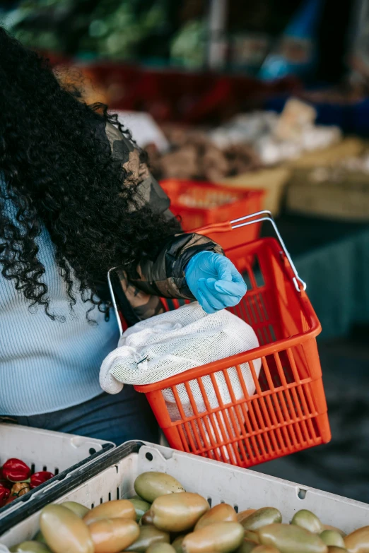 a woman holding a basket of fruit at a market, by Matt Cavotta, pexels, process art, blue gloves, holding a bucket of kfc, african american young woman, closeup of a butcher working