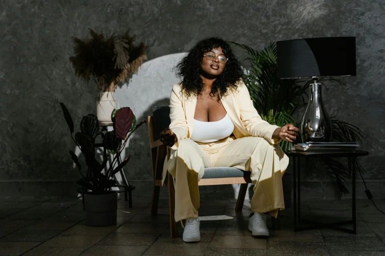 a woman sitting in a chair next to a lamp, inspired by Esaias Boursse, trending on pexels, lizzo, wearing a track suit, high quality picture, center focused