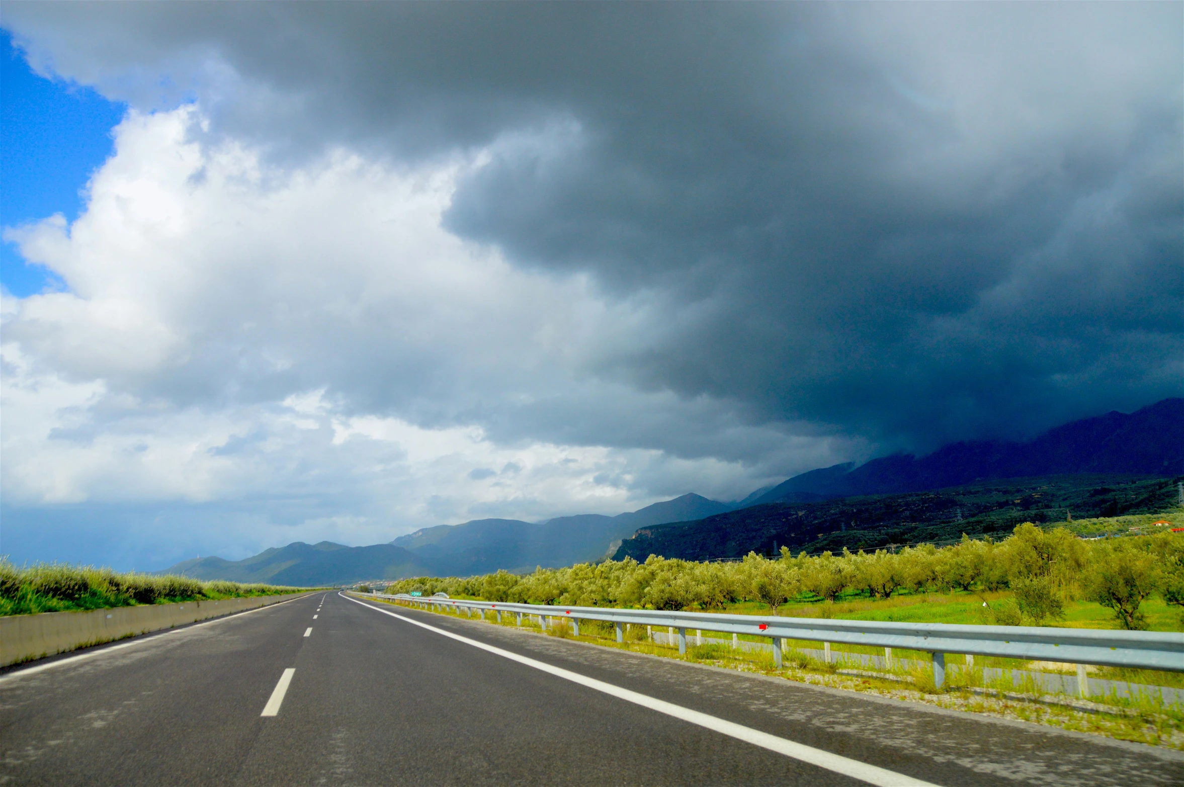 a highway on a cloudy day with mountains in the distance, a picture, vacation photo, thunderstorms, panoramic, thumbnail