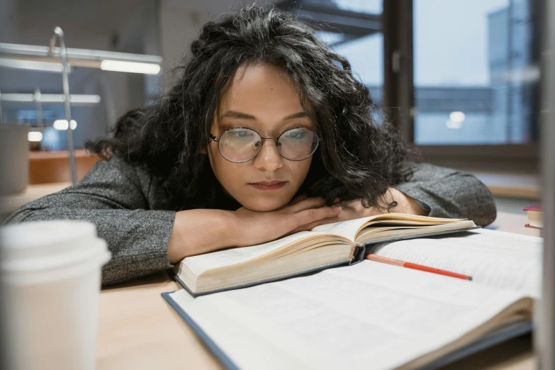 a woman sitting at a table reading a book, pexels contest winner, academic art, sleepy expression, girl wearing round glasses, gif, mid shot photo