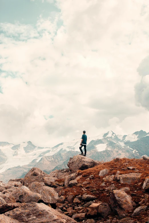 a person standing on top of a rocky hill, trending on pexels, whistler, humans exploring, brown, in the clouds