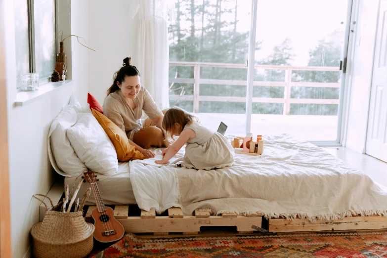 a woman sitting on top of a bed next to a child, pexels contest winner, pallet, sustainable materials, manuka, profile image