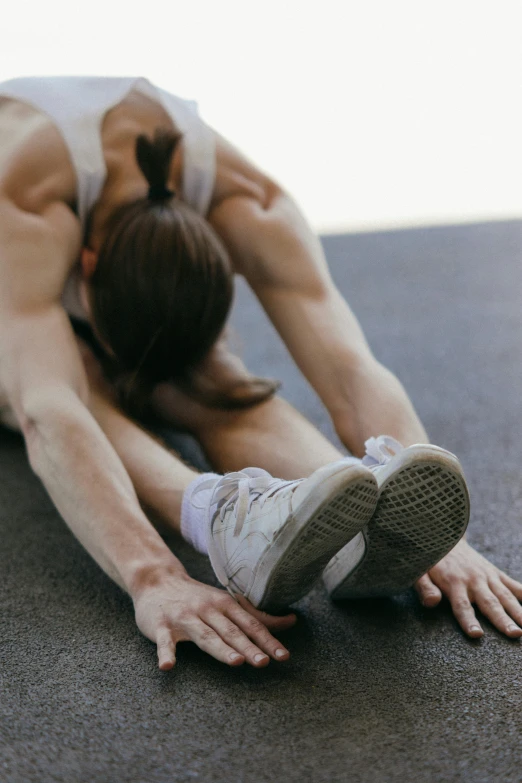 a woman doing a yoga pose on the ground, by Carey Morris, pexels contest winner, renaissance, defined muscles, running shoes, half turned around, mechanics