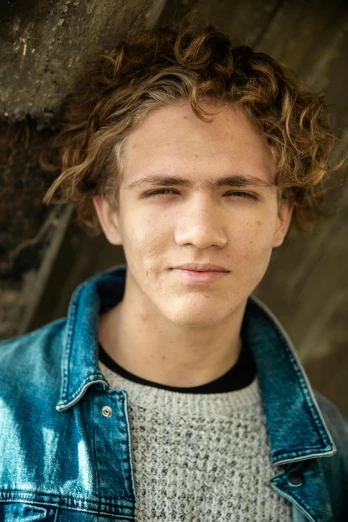 a close up of a person wearing a jacket, by Jacob Toorenvliet, light brown messy hair, male teenager, promo image, curly and short top hair
