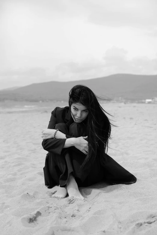 a woman sitting on top of a sandy beach, a black and white photo, by Alexis Grimou, hurufiyya, with his long black hair, in pain, bae suzy, khyzyl saleem