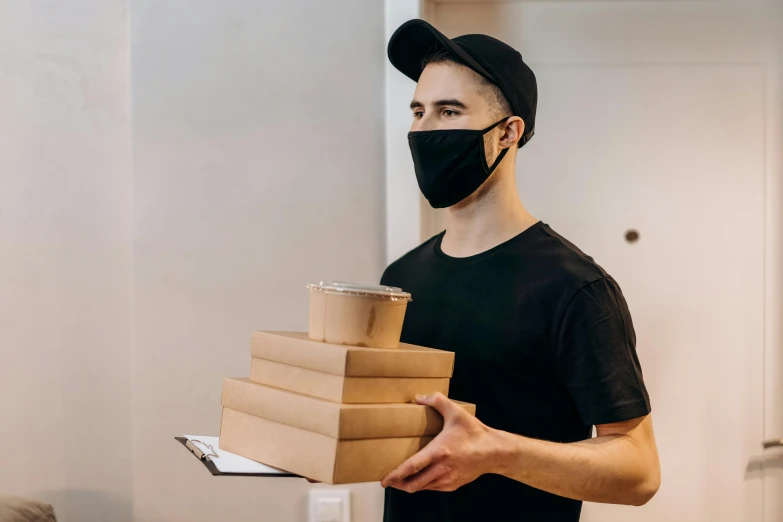 a man wearing a face mask holding a stack of boxes, by Adam Rex, pexels contest winner, he wears dark visors, server in the middle, lachlan bailey, logo for lunch delivery