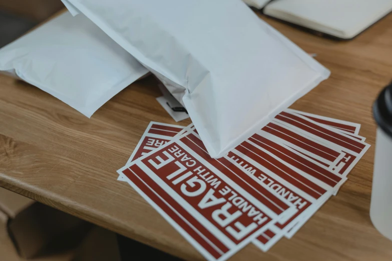 a pile of stickers sitting on top of a wooden table, pexels contest winner, private press, maroon and white, delivering mail, bandages, striped