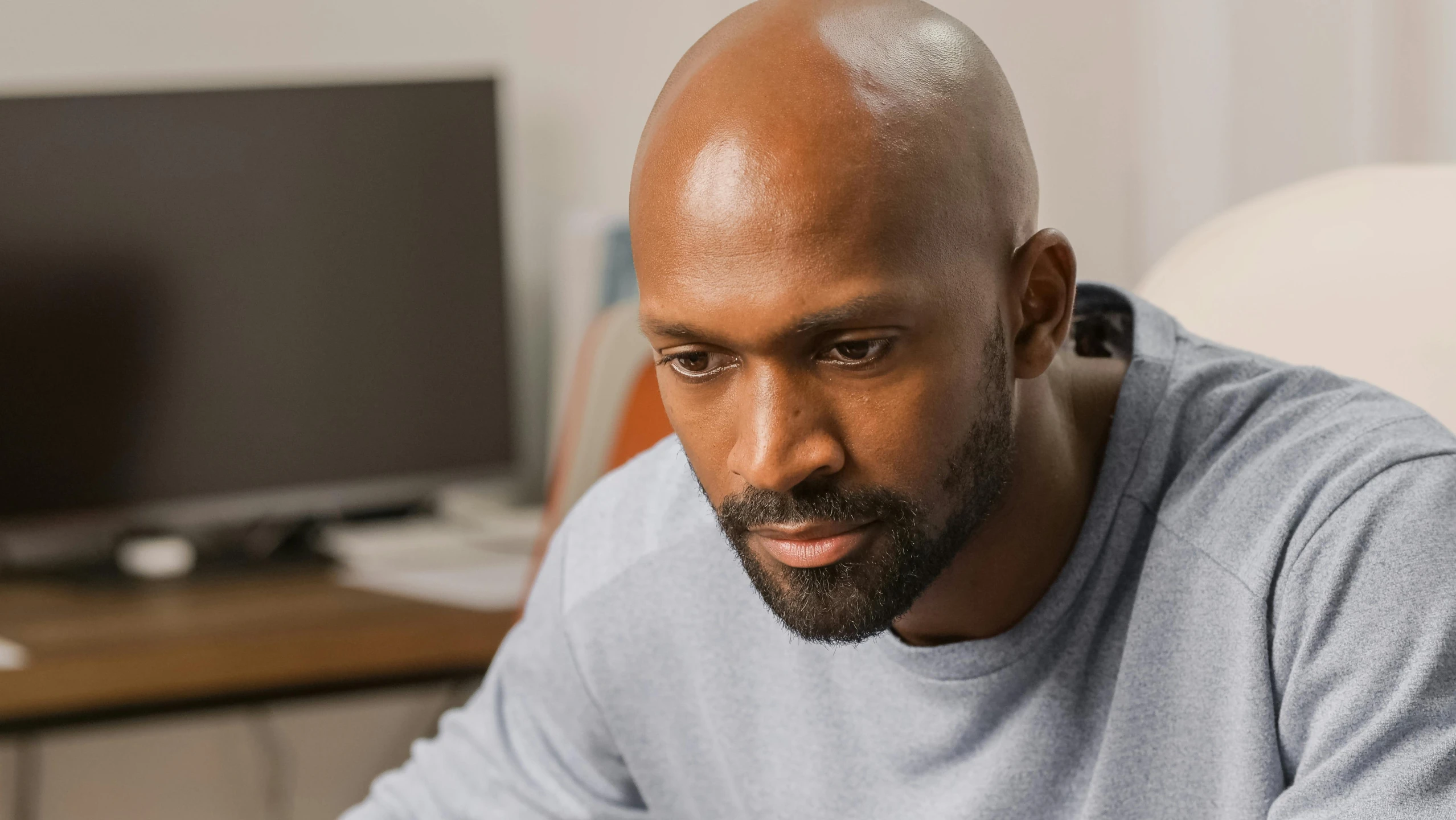 a man sitting in front of a laptop computer, inspired by Terrell James, bald with short beard, focused stare, candid shot, atiba jefferson