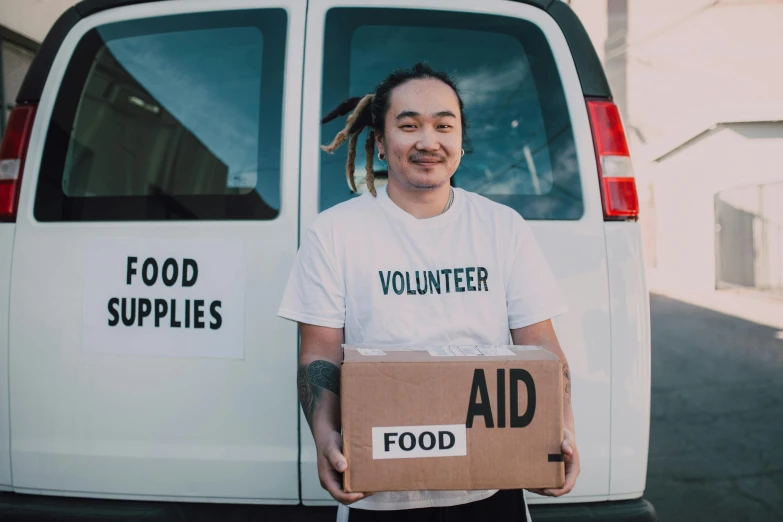 a man holding a box in front of a van, by Francis Helps, pexels contest winner, hurufiyya, hunger, te pae, nanae kawahara, headshot profile picture