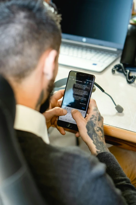 a man sitting at a desk using a cell phone, by Matthias Stom, pexels, worksafe. instagram photo, tattooed, in an call centre office, thumbnail