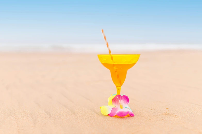 a yellow cocktail glass sitting on top of a sandy beach, ecommerce photograph, yellow, flowers around, carnival