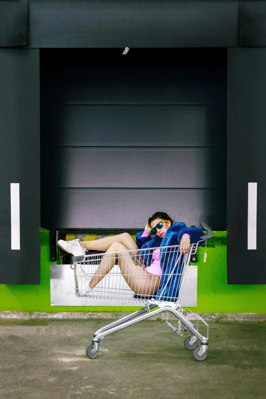 a man sitting in a shopping cart in front of a building, inspired by Ren Hang, pexels contest winner, bra and shorts streetwear, young lady, green legs, sitting on a store shelf