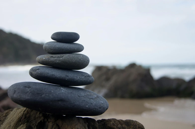 a stack of rocks sitting on top of a rock, by Jessie Algie, unsplash, minimalism, relaxing on the beach, acupuncture treatment, grey, slate