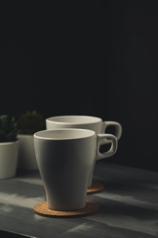 a couple of cups sitting on top of a table, a still life, unsplash, photorealism, medium format. soft light, promo image, dimly lit, close - up studio photo