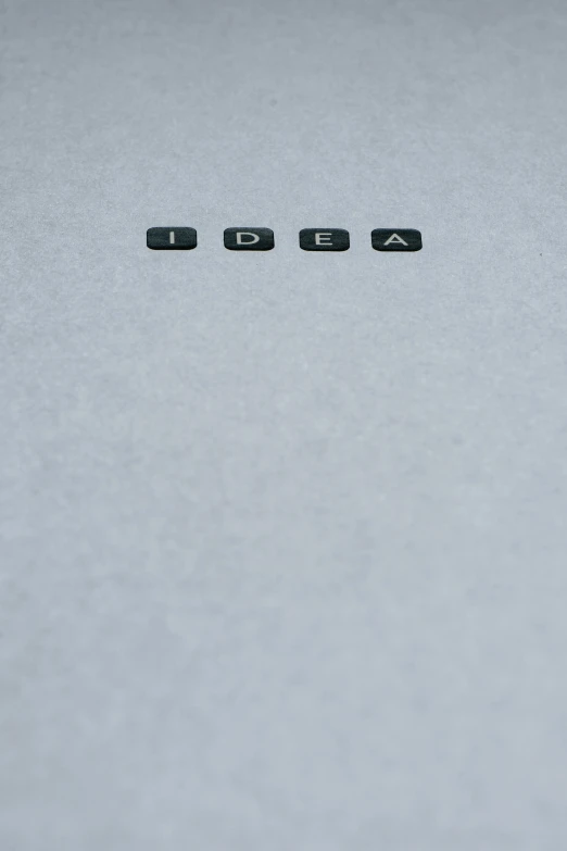 the word igua spelled in black letters on a white surface, an album cover, by Adam Rex, unsplash, conceptual art, lightbulb, grey, blank paper, 15081959 21121991 01012000 4k