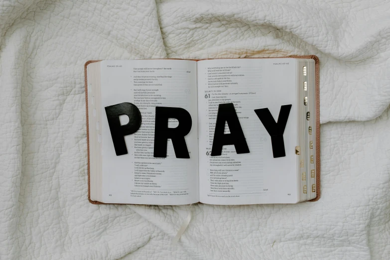 an open book with the word pray written on it, trending on pexels, hurufiyya, fan favorite, christian saint, emergency, full-body