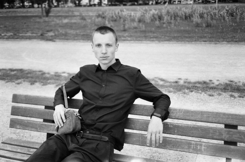 a black and white photo of a man sitting on a bench, a black and white photo, andrey surnov, thin aged 2 5, beskinski, taken in the late 2010s