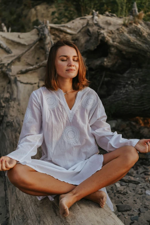 a woman sitting in a lotus position on a rock, a portrait, unsplash, wearing a linen shirt, wearing nanotech honeycomb robe, white lace clothing, wearing white v - neck top