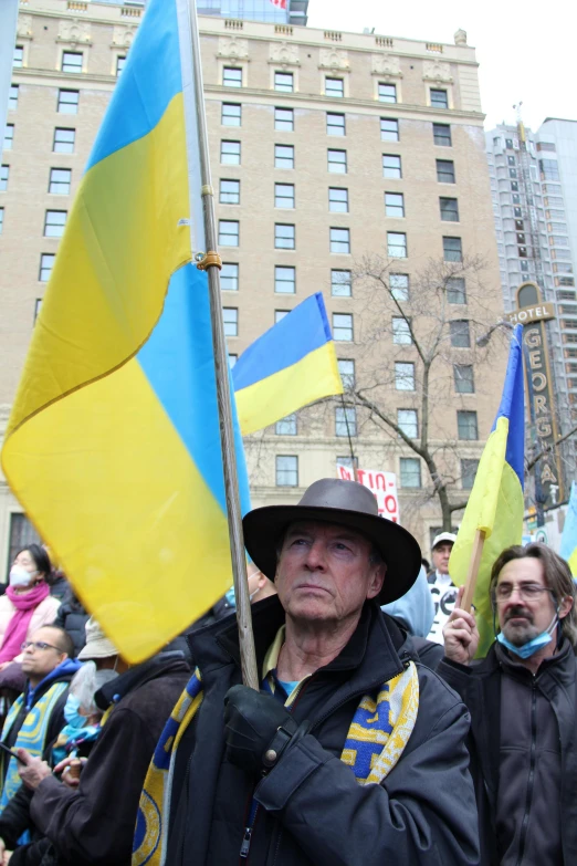 a group of people walking down a street holding flags, ukrainian, a photo of a man, yellow and blue, thumbnail