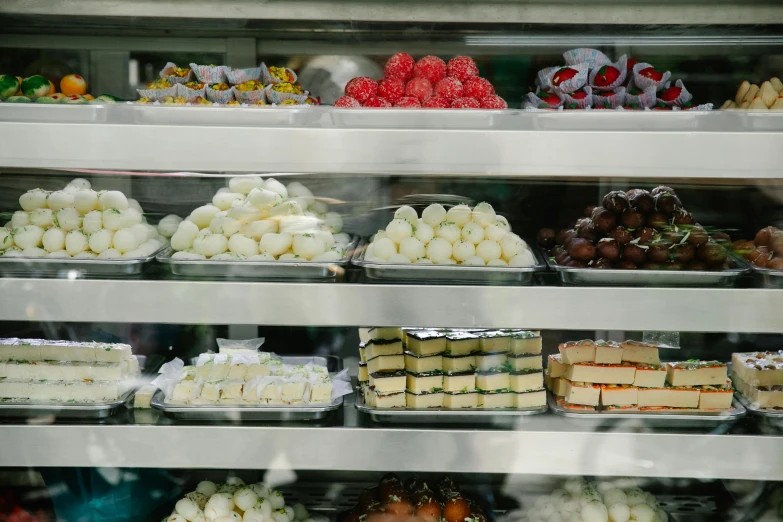 a display case filled with lots of different types of cakes, pexels, lots of mozzarella balls, on the sidewalk, 2000s photo, square