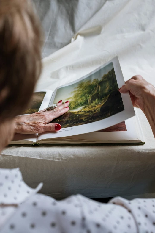 a woman reading a book on a bed, a photorealistic painting, pexels contest winner, old photobook, an elderly, nature painting, on a white table