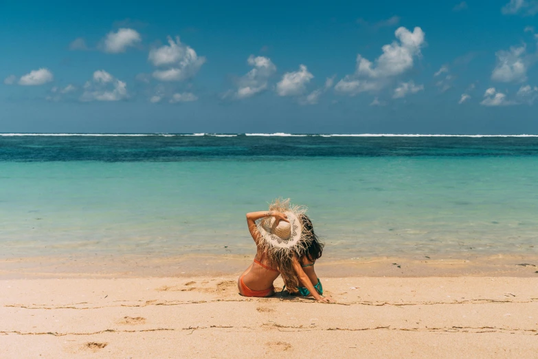 a woman sitting on top of a sandy beach next to the ocean, bali, tanned, over it's head, all around