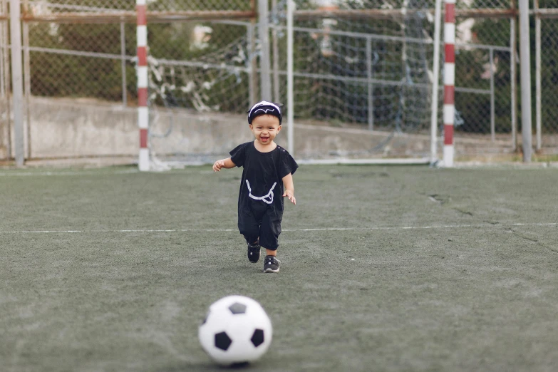 a young boy running towards a soccer ball, inspired by Master of the Bambino Vispo, pexels contest winner, happening, wearing black dress and hat, toddler, wearing the number 1 headband, small horns