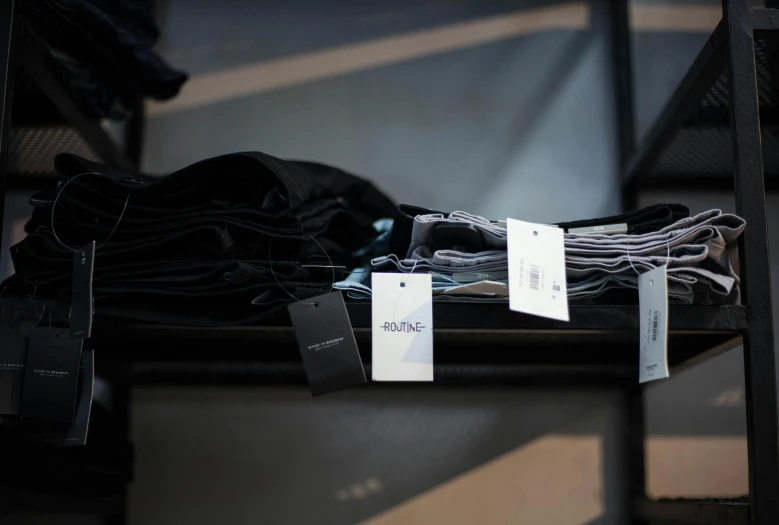 a pile of clothes sitting on top of a metal shelf, labels, wearing black clothes, inspect in inventory image, ignant