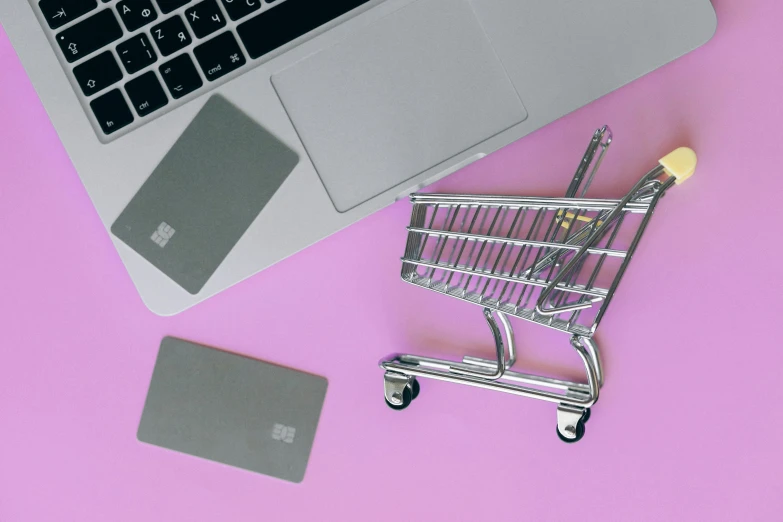 a shopping cart next to a laptop and a credit card, by Julia Pishtar, pexels, magic realism, purple and pink, instagram post, flat lay, promo image