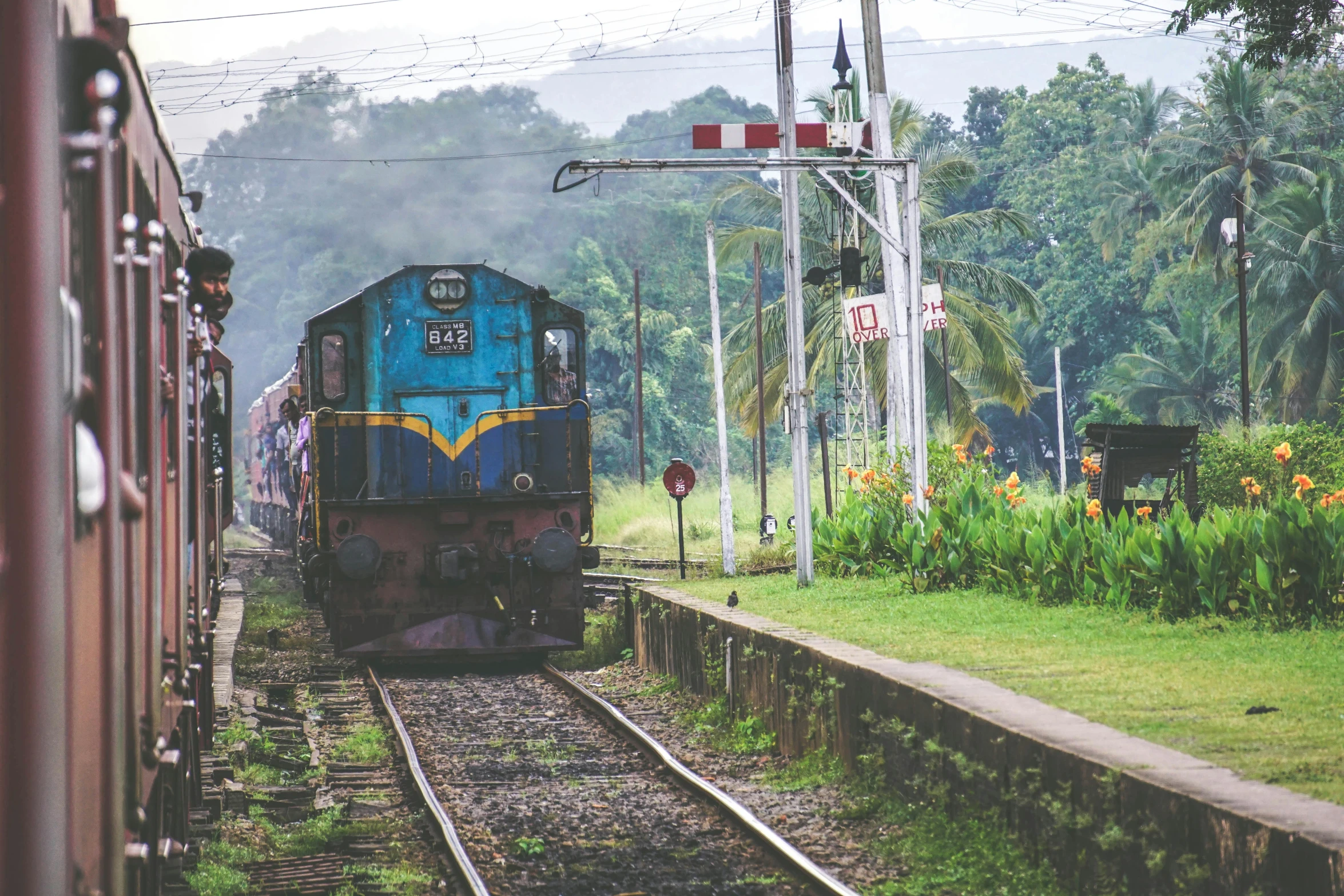 a train traveling down train tracks next to a lush green forest, hurufiyya, hindu aesthetic, 90s photo