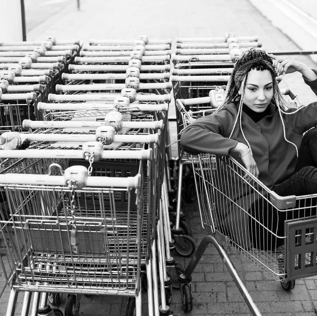 a black and white photo of a woman sitting in a shopping cart, by Matija Jama, pexels, realism, streetwear, getting groceries, laying down, symmetrical