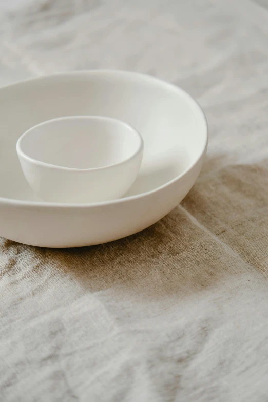 a white cup and saucer sitting on a table, inspired by Josefina Tanganelli Plana, minimalism, medium close up, bowl, two, cast