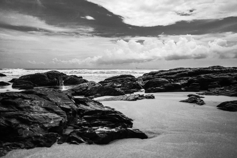 a black and white photo of rocks on a beach, a black and white photo, unsplash, sri lankan landscape, skies, medium format, today\'s featured photograph 4k