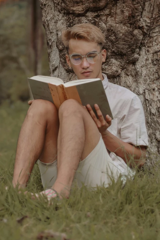 a man sitting under a tree reading a book, by Jacob Toorenvliet, pexels contest winner, hyperrealism, an epic non - binary model, tommy 1 6 years old, white reading glasses, innocent look