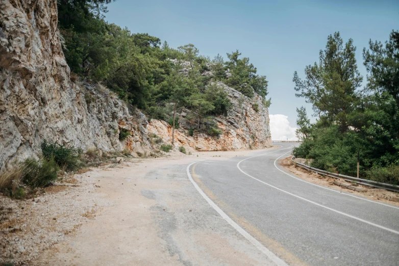 a motorcycle is parked on the side of the road, unsplash, les nabis, greek white marble, hill with trees, pov photo