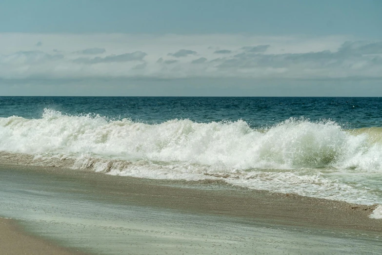 a man riding a surfboard on top of a sandy beach, unsplash, renaissance, blue crashing waves, sparsely populated, craigville, ignant