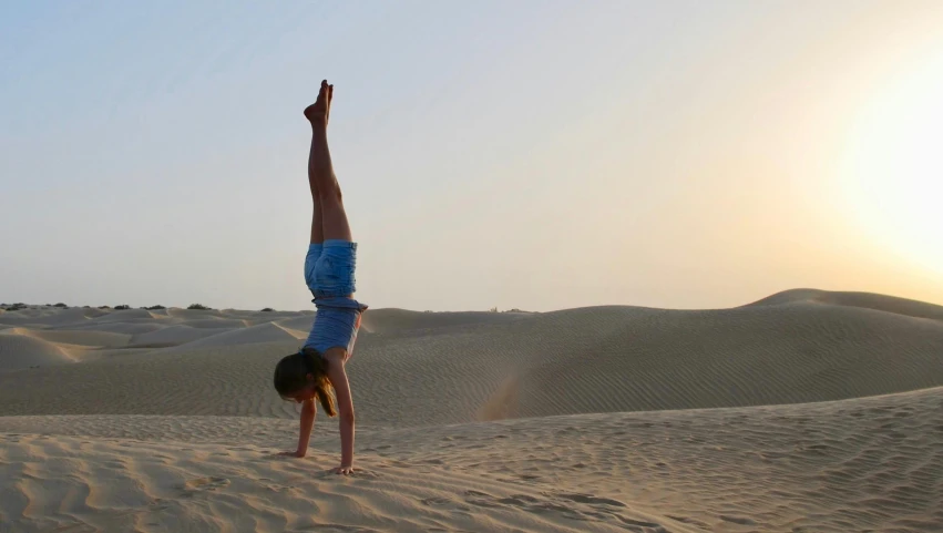 a person doing a handstand in the desert, by Arabella Rankin, pexels contest winner, arabesque, girl graceful, oman, yoga pose, profile image