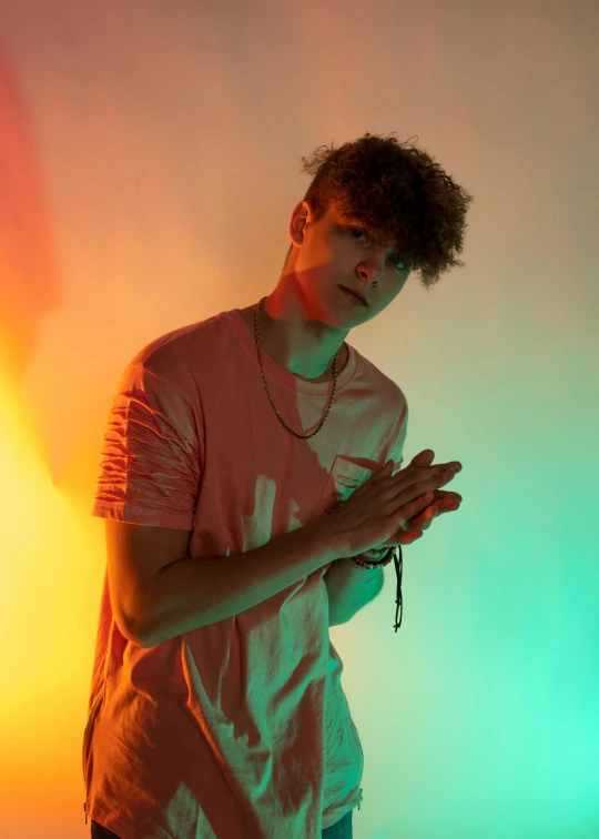 a man standing in front of a colorful light, an album cover, inspired by John Luke, pexels, he has short curly brown hair, bisexual lighting, doing a hot majestic pose, ansel ]