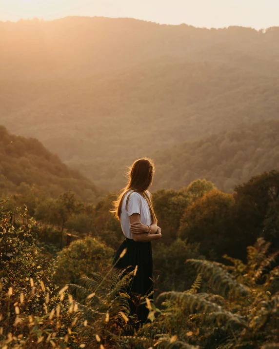 a woman standing on top of a lush green hillside, unsplash contest winner, naturalism, looking off into the sunset, amongst foliage, human staring blankly ahead, slightly minimal